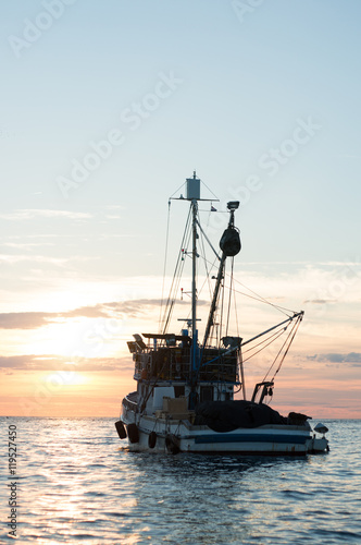 fishing boat sailing at sunset