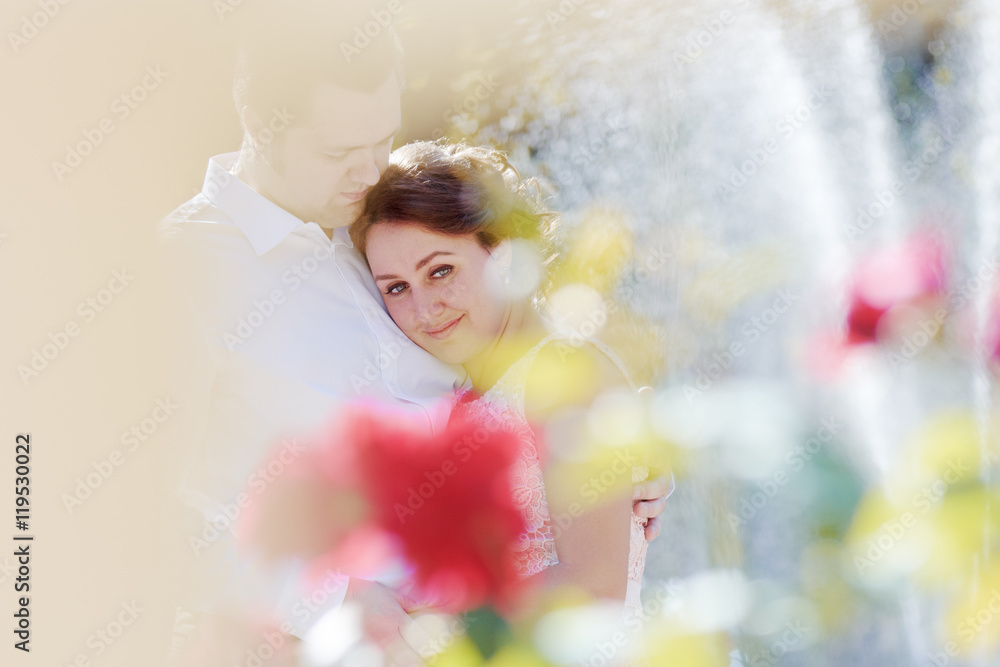 Embrace of couple in love. Emotional portrait of happy bride. Beautiful city fountain, lit by sun. Backlight Embrace of couple in love. Emotional portrait of happy bride. Beautiful city fountain, lit by sun. Backlight