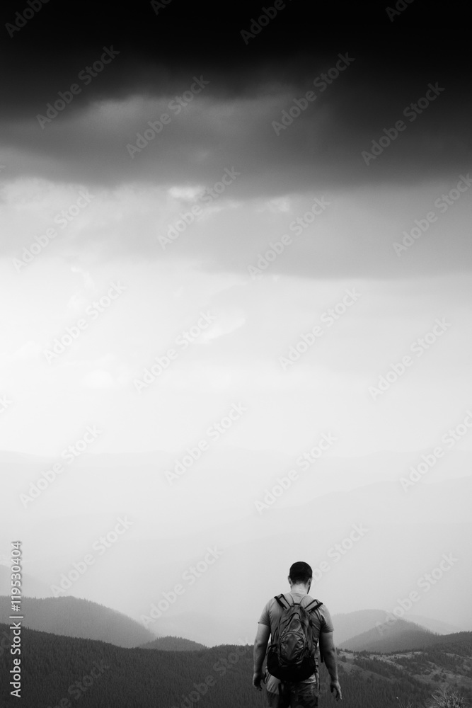 Tourist on top of mountain. Man relax and enjoy beautiful panorama of mountain ranges. Rest in mountains. Mountain landscape. Black and white photo