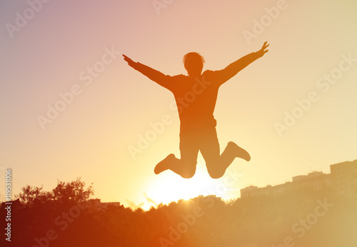 Silhouette of man jumping at sunset sky, happiness