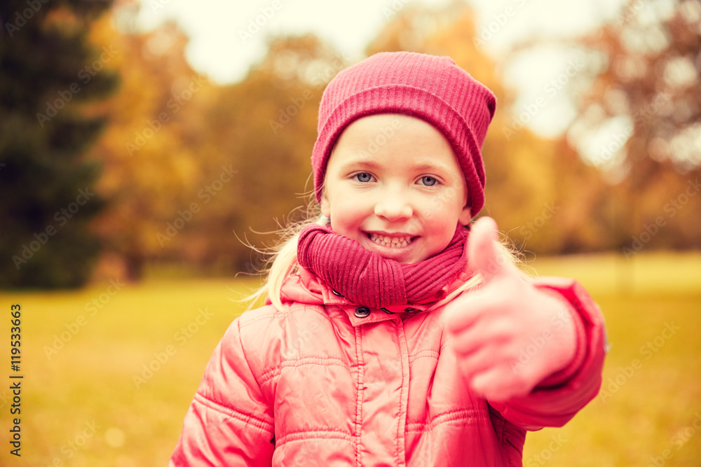 happy little girl showing thumbs up in autumn park happy little girl showing thumbs up in autumn park