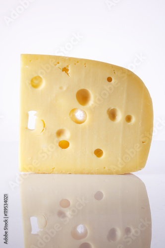 a piece of cheese with the large holes on a light background with a gradient.