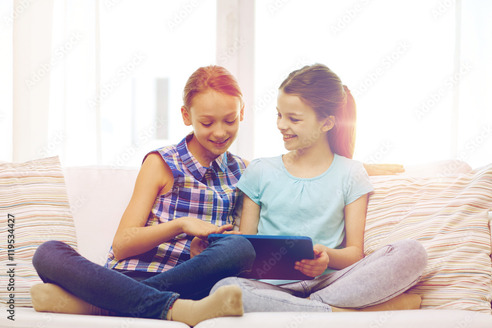 happy girls with tablet pc sitting on sofa at home happy girls with tablet pc sitting on sofa at home