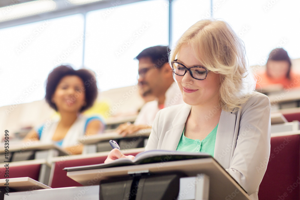 student girl writing to notebook in lecture hall student girl writing to notebook in lecture hall