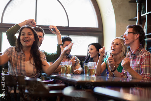 friends with beer watching football at bar or pub © Syda Productions
