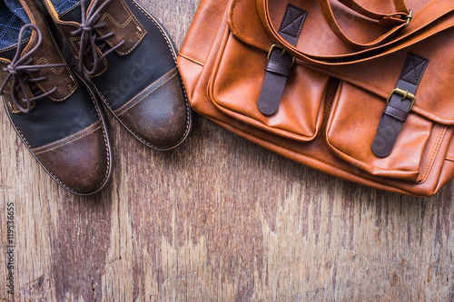 Men's accessories with brown leather bag and brown shoes, flat lay, top view on wooden background