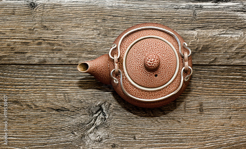 Red brown ceramic teapot standing on a wooden table. Used in the tea ceremony