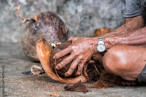 hand while cutting and opening fresh coconut