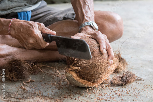 hand while cutting and opening fresh coconut