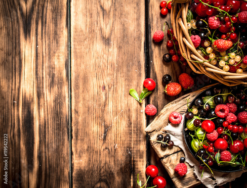 Fresh berries in an old basket. On wooden table.