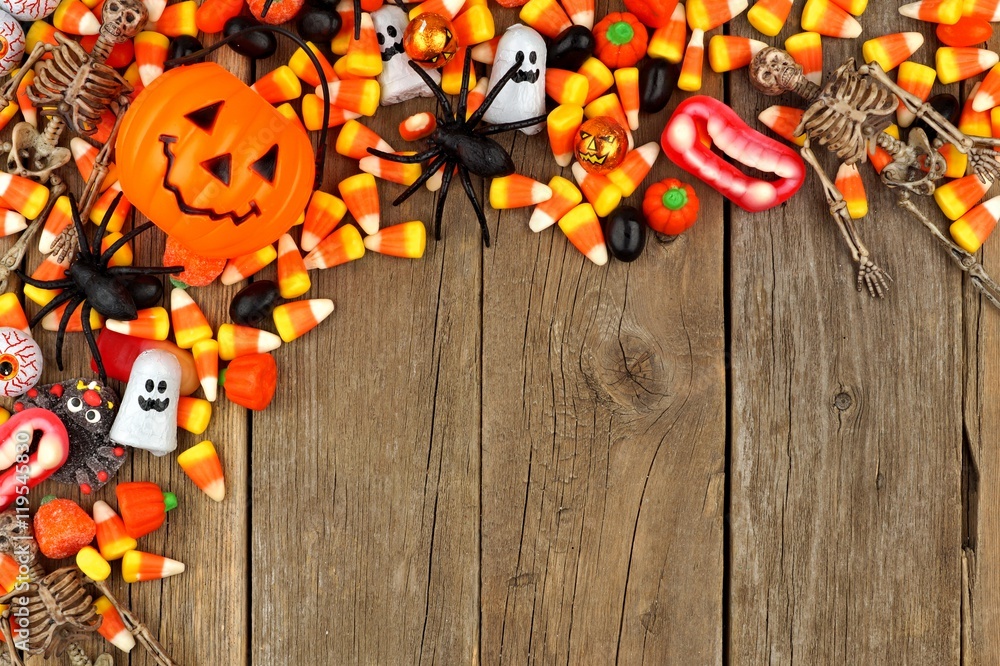 Halloween candy and decor top corner border against a rustic wood background Halloween candy and decor top corner border against a rustic wood background