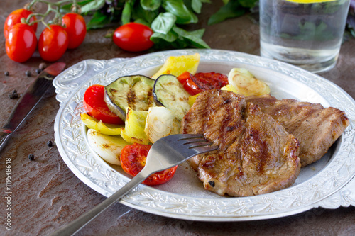 Grilled steak meat pork and grilled vegetables on brown stone ba