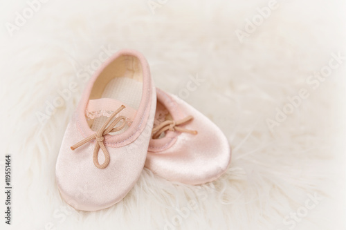 Light pink ballet dance shoes on a white fluffy background