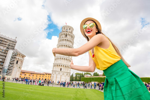 Young female traveler having fun in front of the famous leaning tower in Pisa old town in Italy. Happy vacations in Italy