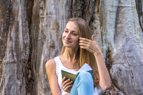 Young woman sitting on the grass and reading book.