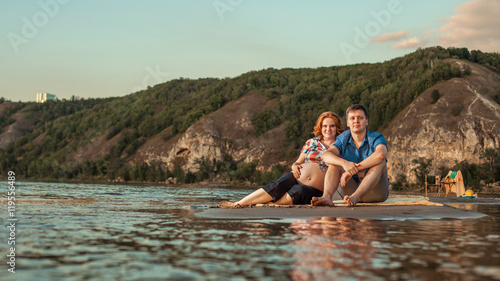 Beautiful couple is sitting on the beach and looking at the came © diter