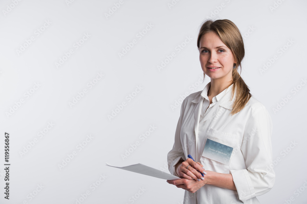 Beautiful nurse smiling and taking notes on a white isolated background Beautiful nurse smiling and taking notes on a white isolated background