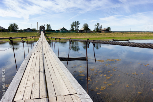 Rural landscape at summer with wooden suspension bridge