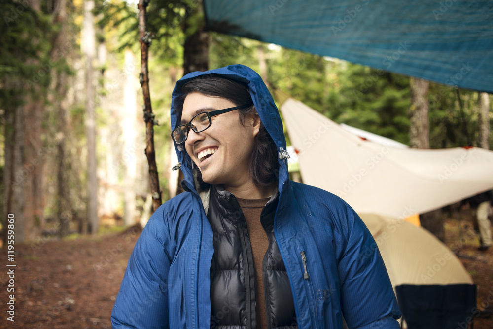 Happy man looking away at campsite in forest Happy man looking away at campsite in forest