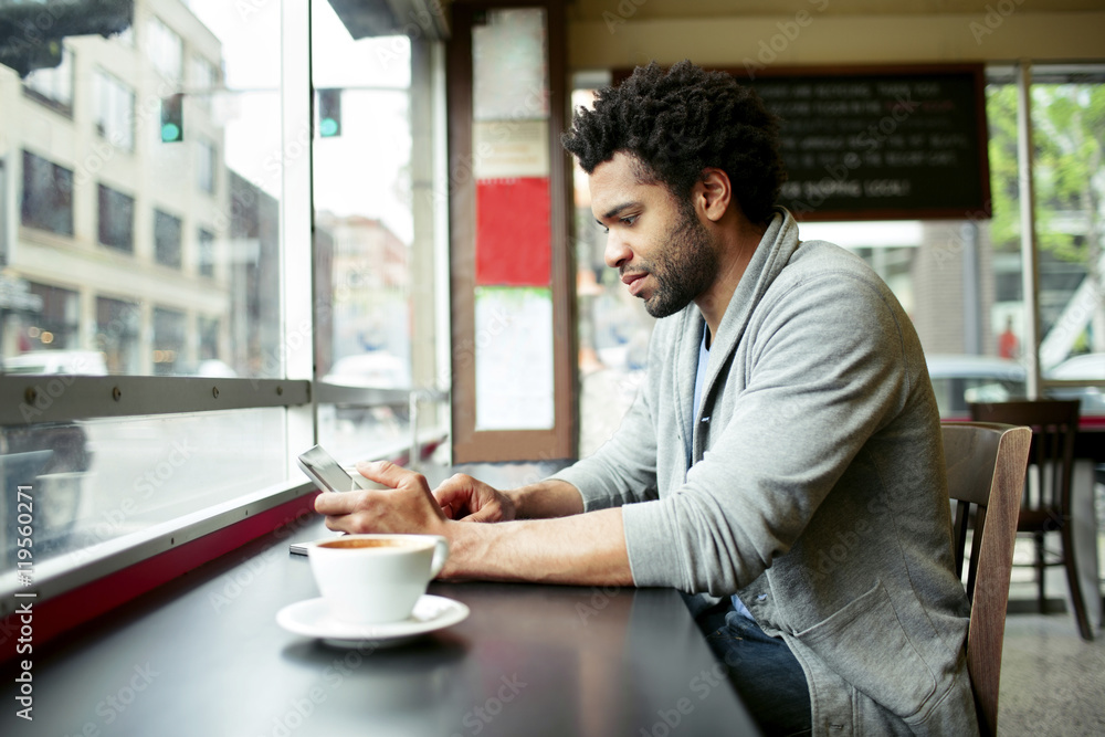 Side view of man using tablet computer at table in cafe Side view of man using tablet computer at table in cafe