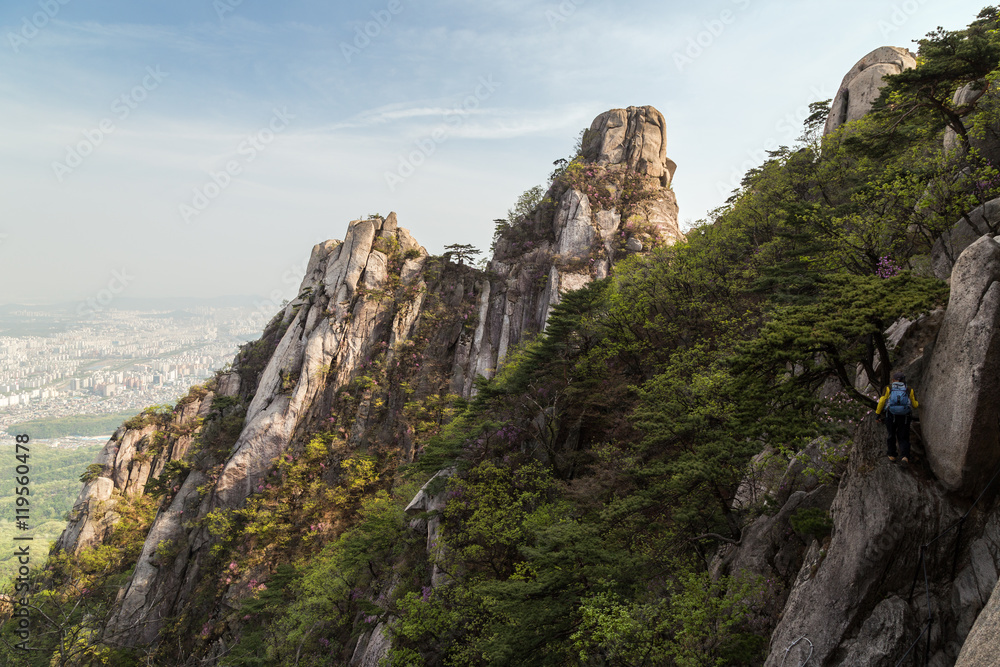 Man hiking on a steep cliff at the Jaunbong Peak on Dobongsan Mountain at the Bukhansan National Park in Seoul, South Korea.