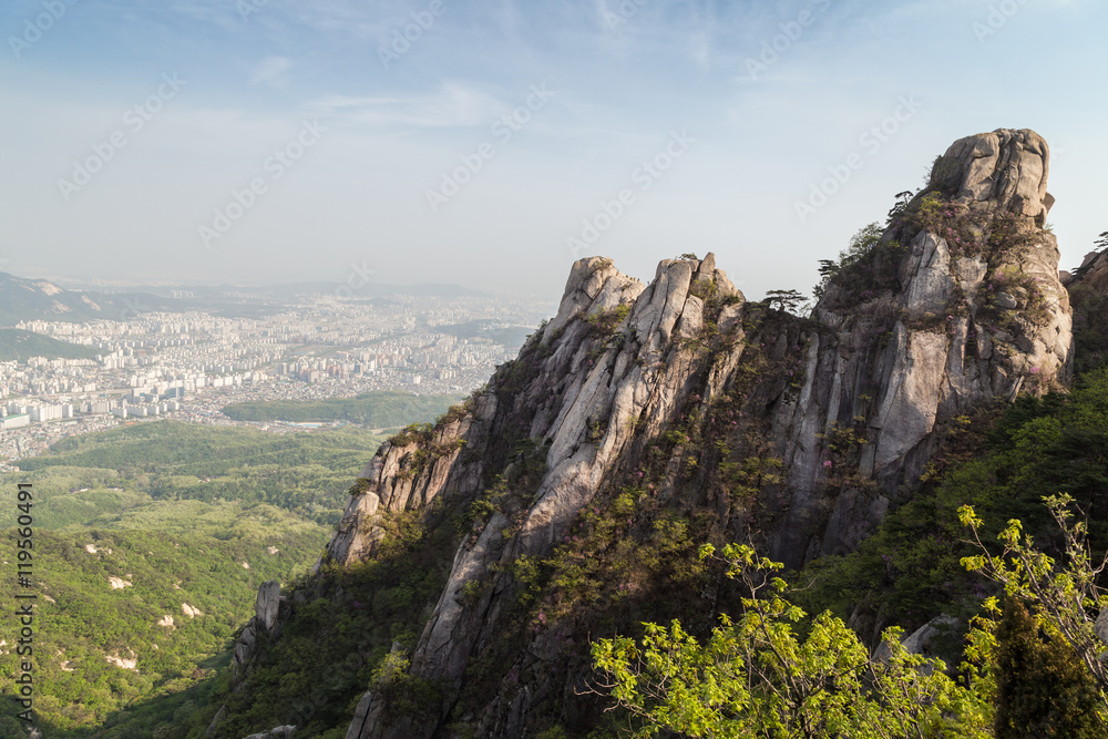 View of the city from above and steep granite peaks of Jaunbong Peak on Dobongsan Mountain at the Bukhansan National Park in Seoul, South Korea.