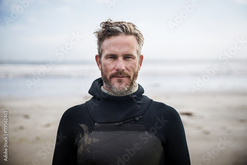 Portrait of confident surfer standing at beach photo