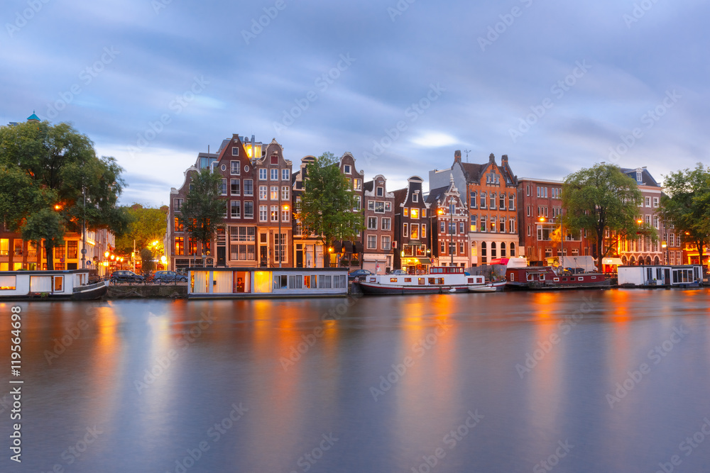 Fototapeta premium Amsterdam canal Amstel with typical dutch houses and boats during twilight blue hour, Holland, Netherlands.
