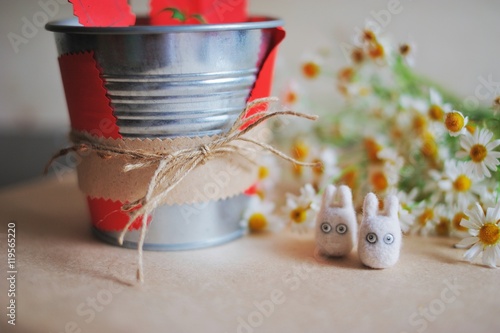 Decorated metal pail, miniature toy Totoro handmade and the bouquet of daisies in the background on the table. Festive home interior. photo