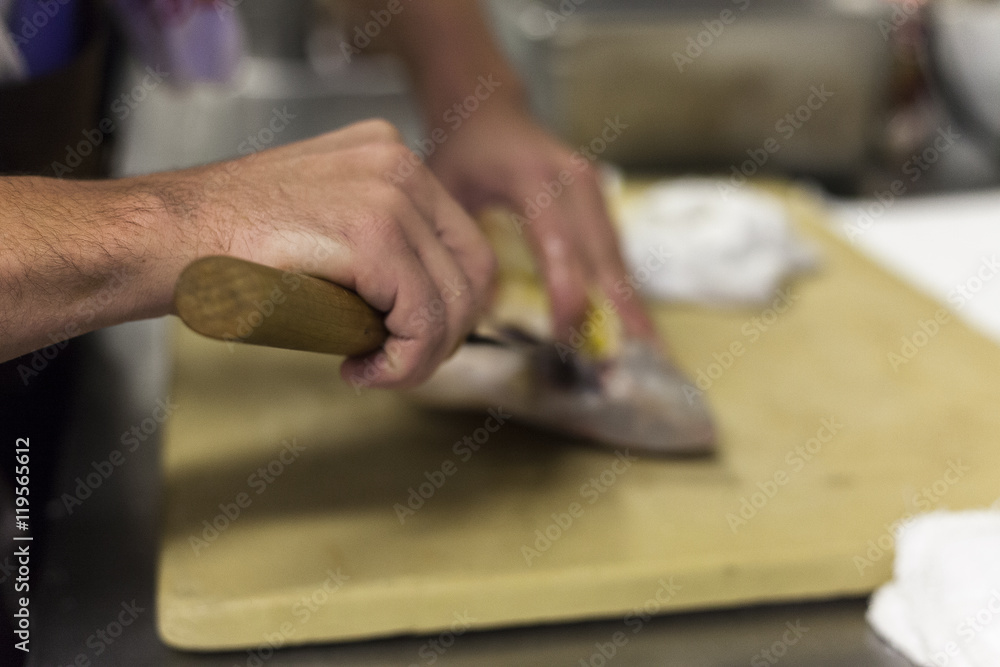 A chef fillets fish before service. A chef fillets fish before service.