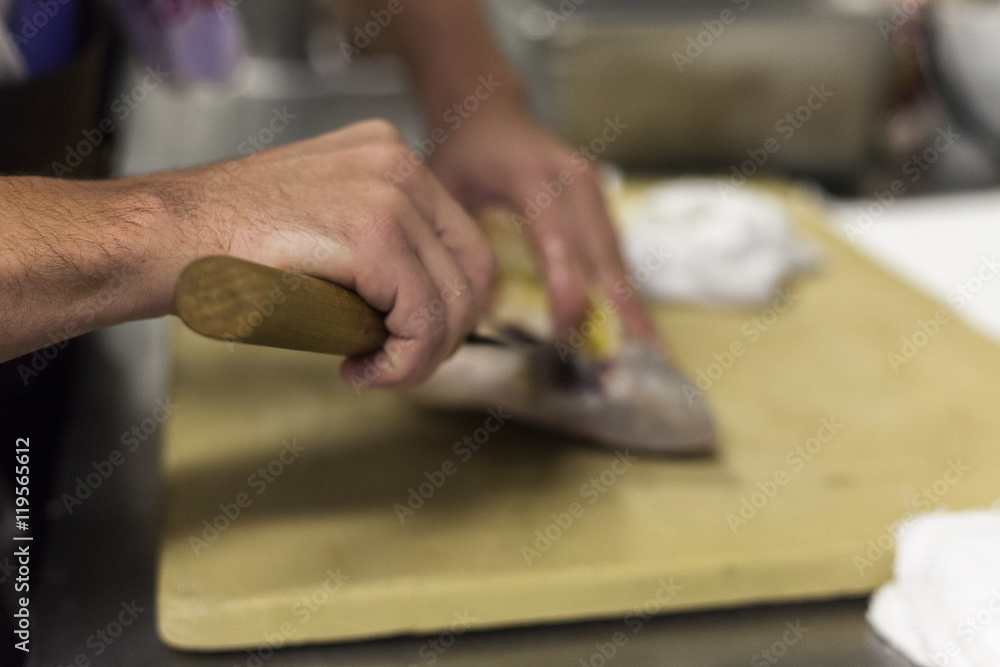 A chef fillets fish before service. 