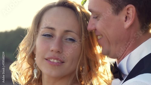 Moment of tenderness. Portrait of sunlit newlywed couple. Groom is kissing bride. photo