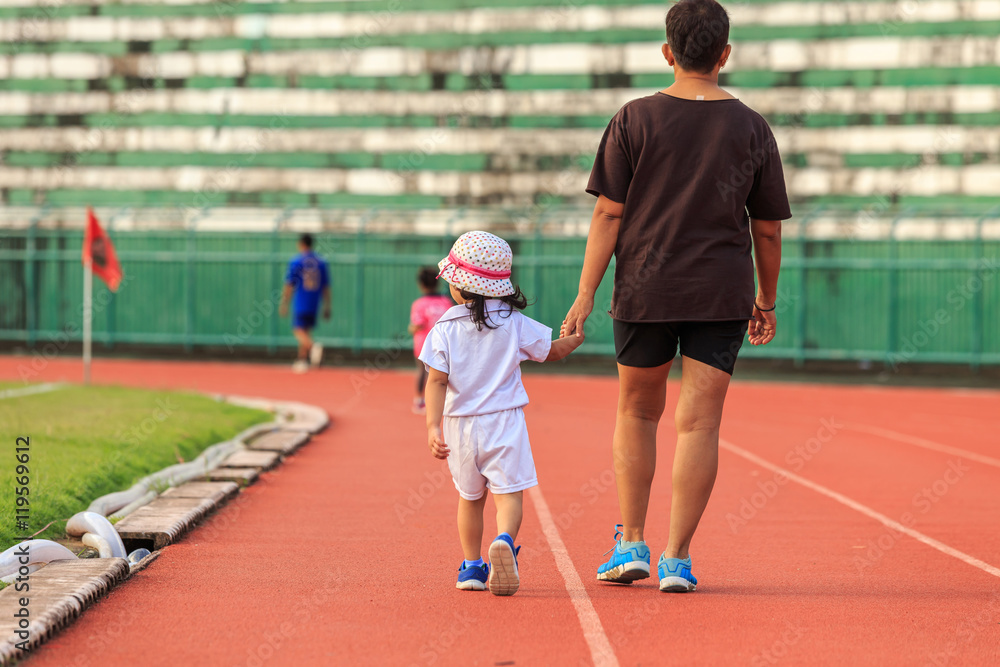 Fototapeta premium Mother holding her daughter hand and walking in running track