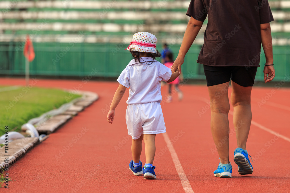 Mother holding her daughter hand and walking in running track
