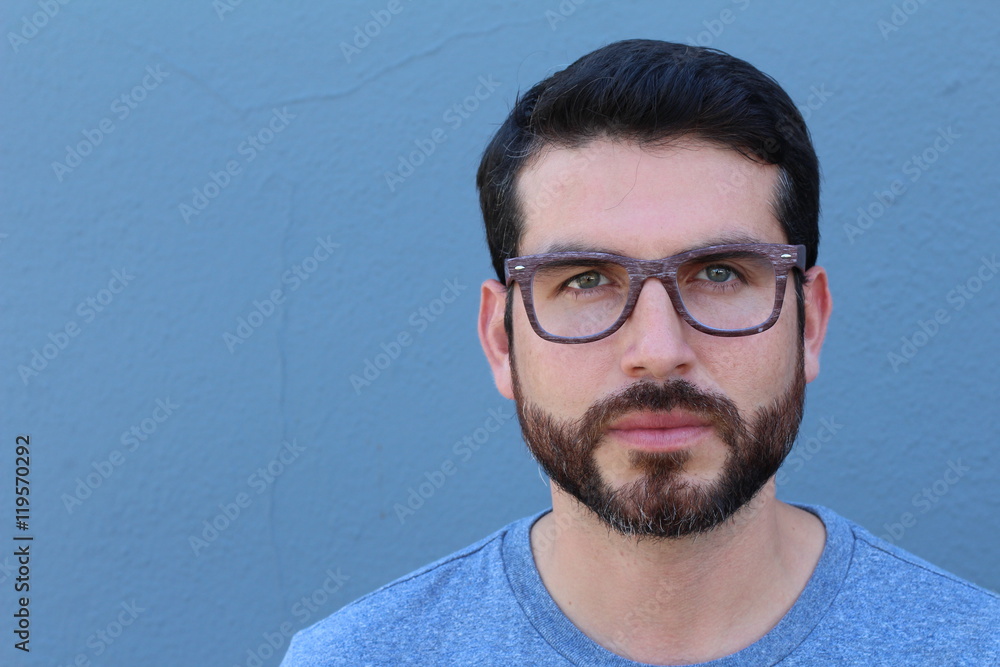 Gorgeous guy wearing glasses leaning on blue wall with copy space. Gorgeous guy wearing glasses leaning on blue wall with copy space.