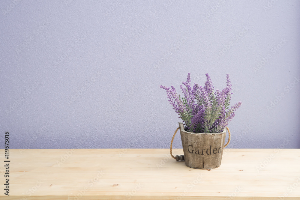 Naklejka premium Wood table with purple lavender flower on flower pot and purple cement wall.