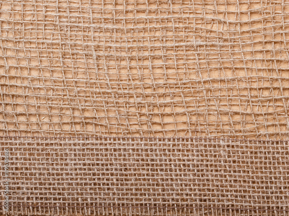 Jute ribbon on burlap cloth background Jute ribbon on burlap cloth background