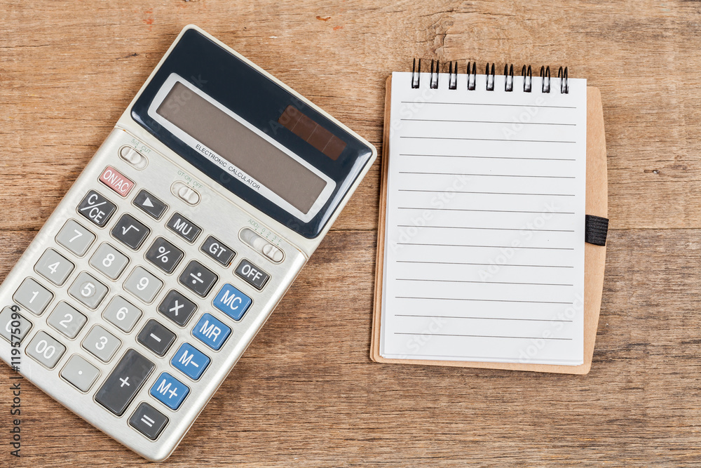notebook showing empty page and calculator on wooden desk notebook showing empty page and calculator on wooden desk