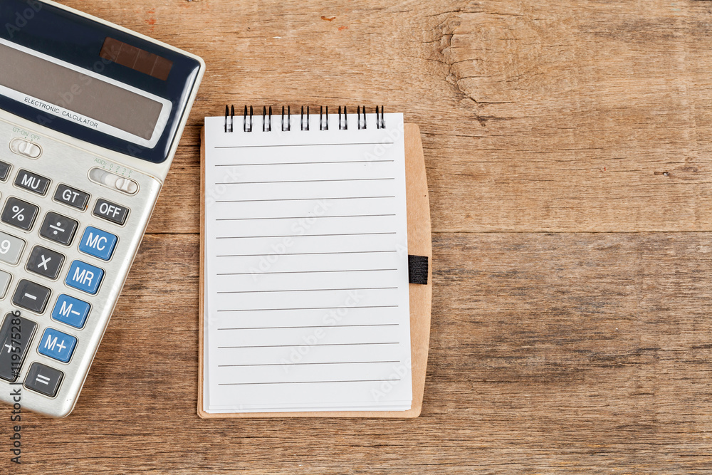 notebook showing empty page and calculator on wooden desk notebook showing empty page and calculator on wooden desk