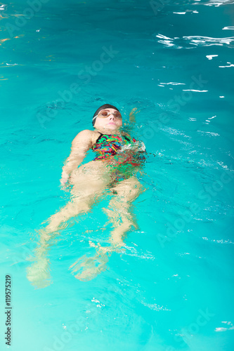 Woman athlete swimming backstroke in pool.