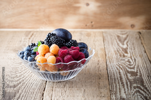 Fresh summer berries and fruits in  glass bowl on wooden rustic