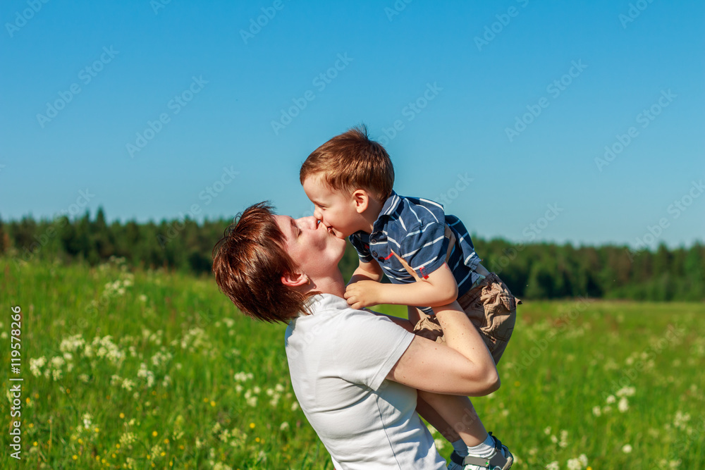 Fototapeta premium Young brunette with short hair playing with his son in the field
