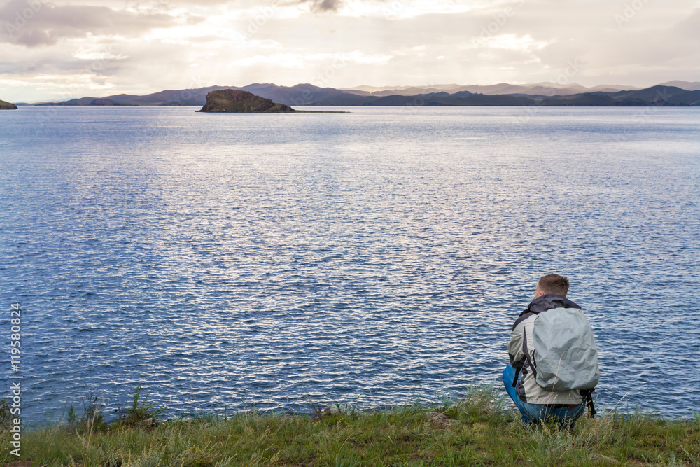 Fototapeta premium Traveler squatting is enjoying the sunrise 