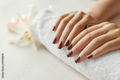 Female hands with brown manicure on towel, closeup
