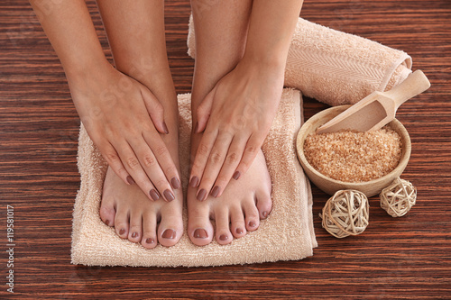 Fototapeta Naklejka Na Ścianę i Meble -  Female hands and feet with brown pedicure on towel