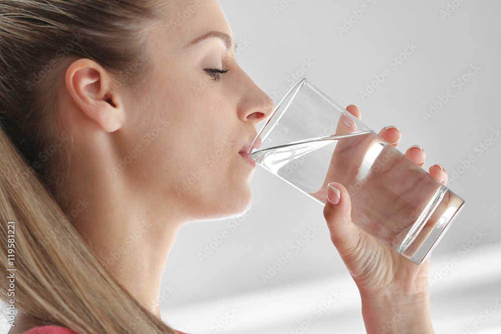 Beautiful girl drinking water on light background Beautiful girl drinking water on light background