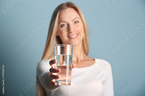 Beautiful girl drinking water on blue background