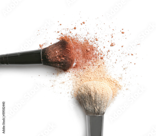 Make up brushes with brown and beige eye shadows on white background