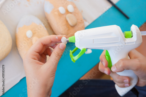 Child using a glue gun on a little stone for making a craft photo