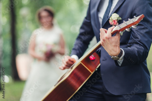 The groom plays the guitar for the bride during wedding ceremony